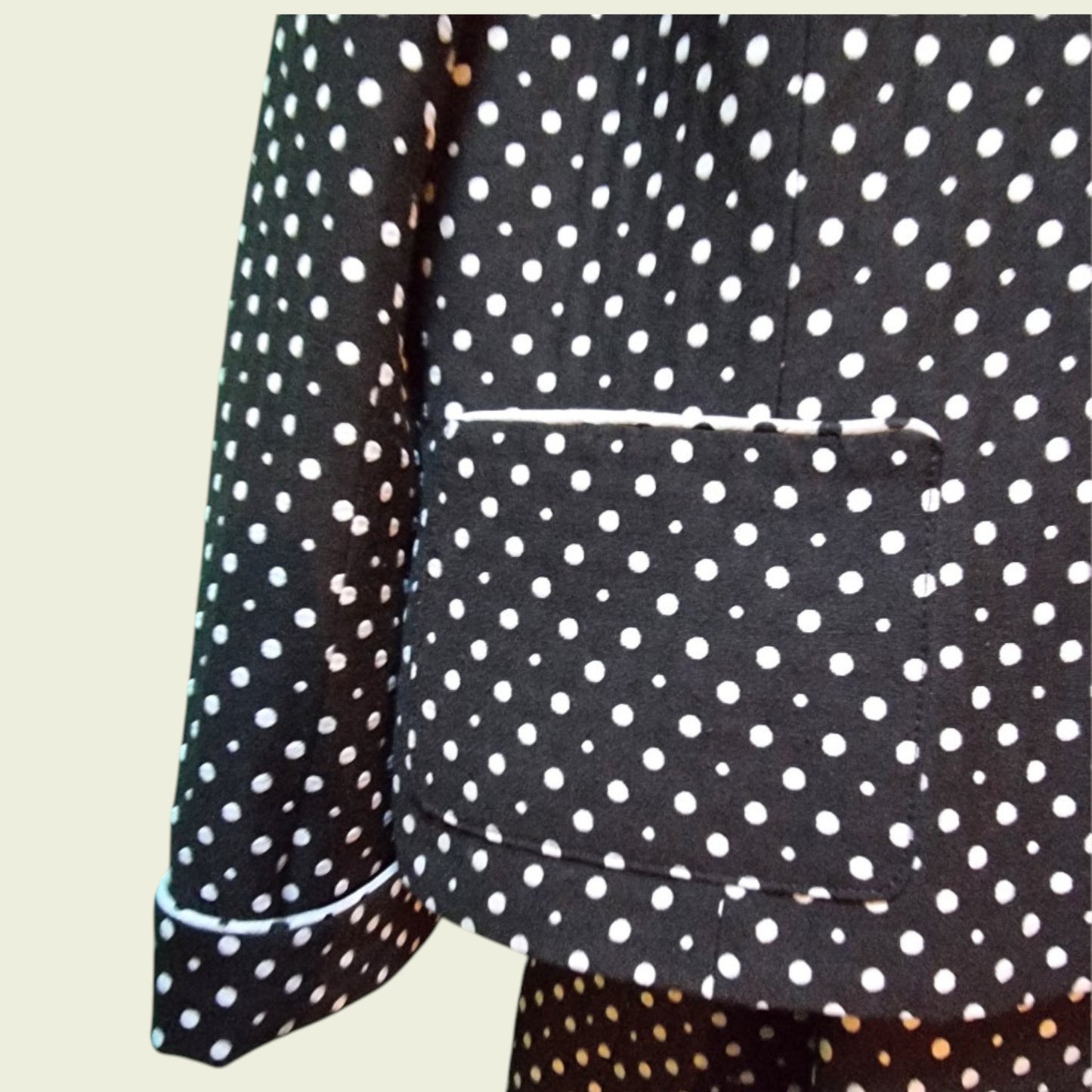 Black jacket with white polka dot pattern on a beige background