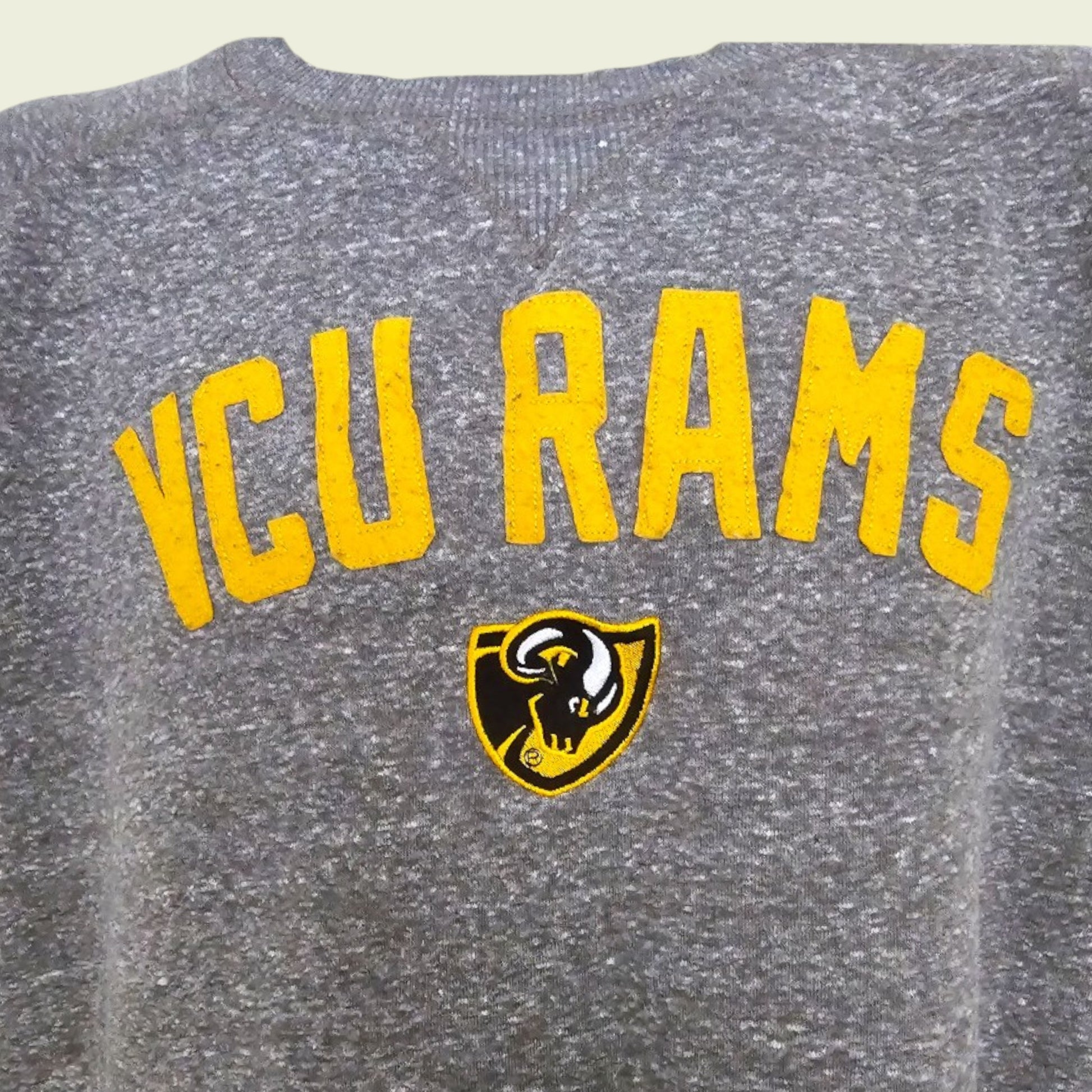Gray sweatshirt with 'VCU Rams' text and logo on a beige background