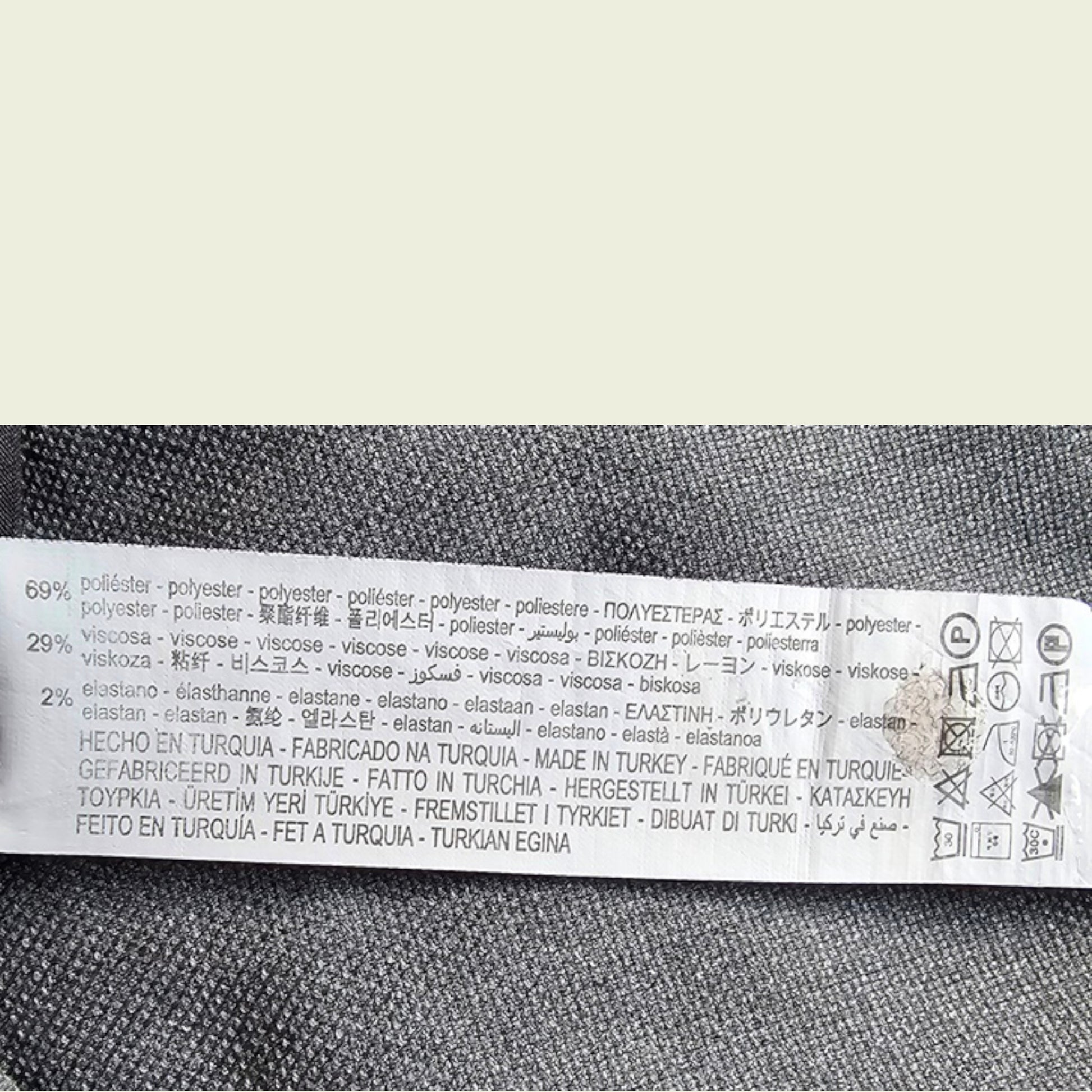 Textile label with fabric composition and care instructions on a gray fabric background