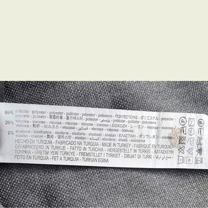 Textile label with fabric composition and care instructions on a gray fabric background