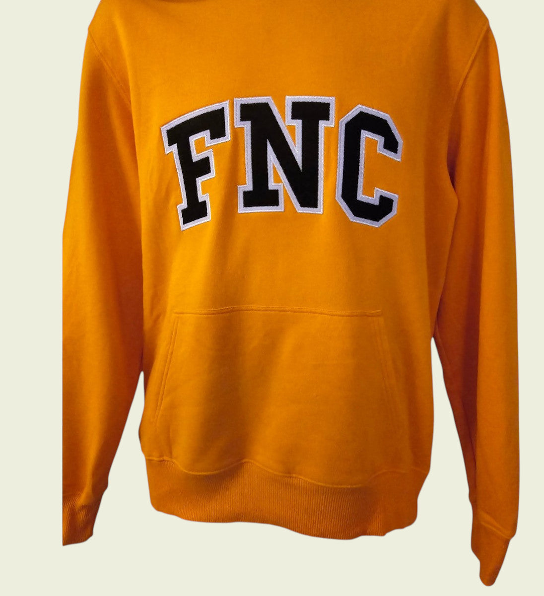 Orange sweatshirt with 'FNC' text on a beige background