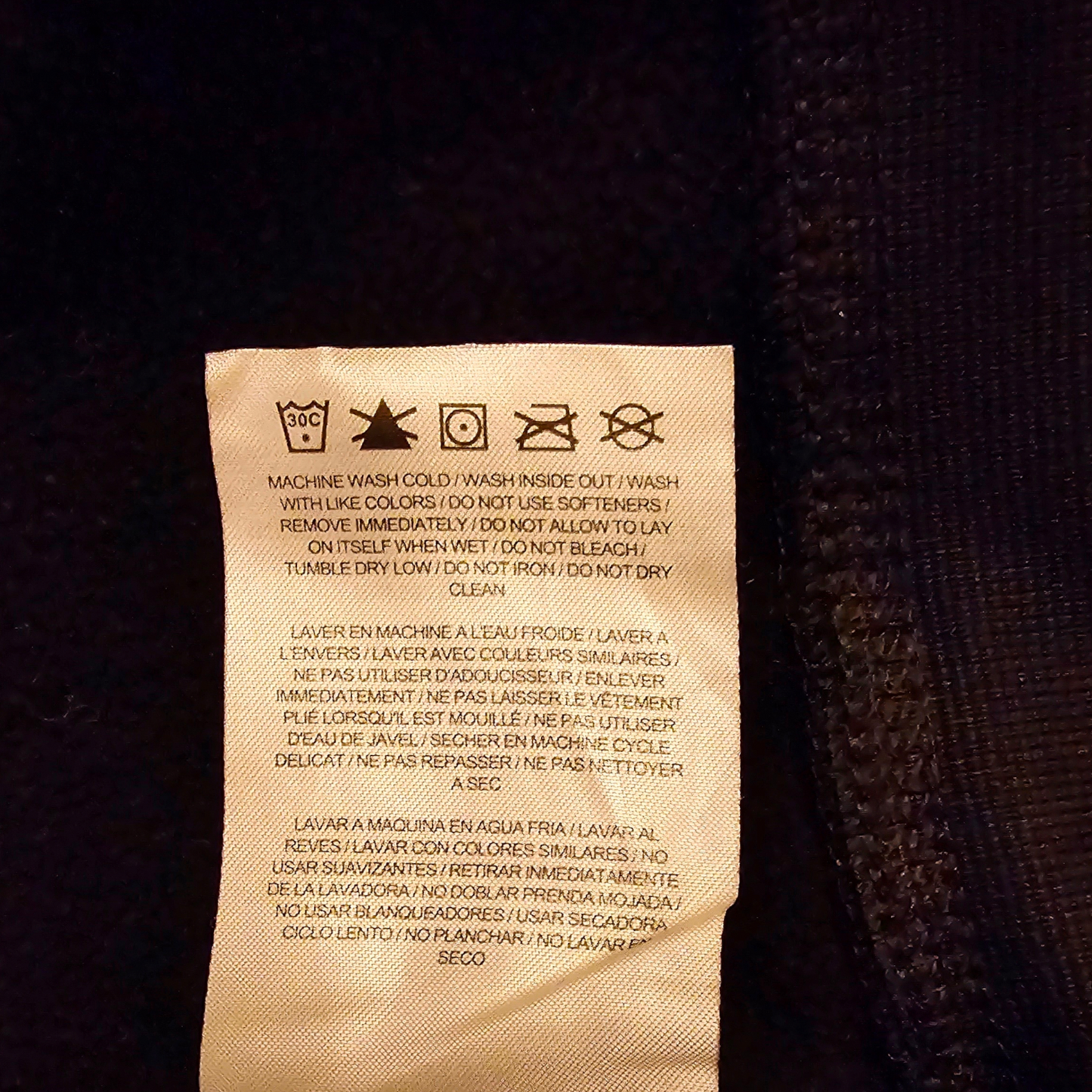 Clothing label with washing instructions on a dark fabric background