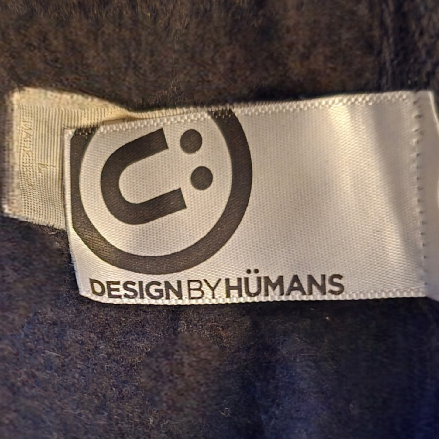 Label with 'Design by Humans' logo on a textured surface