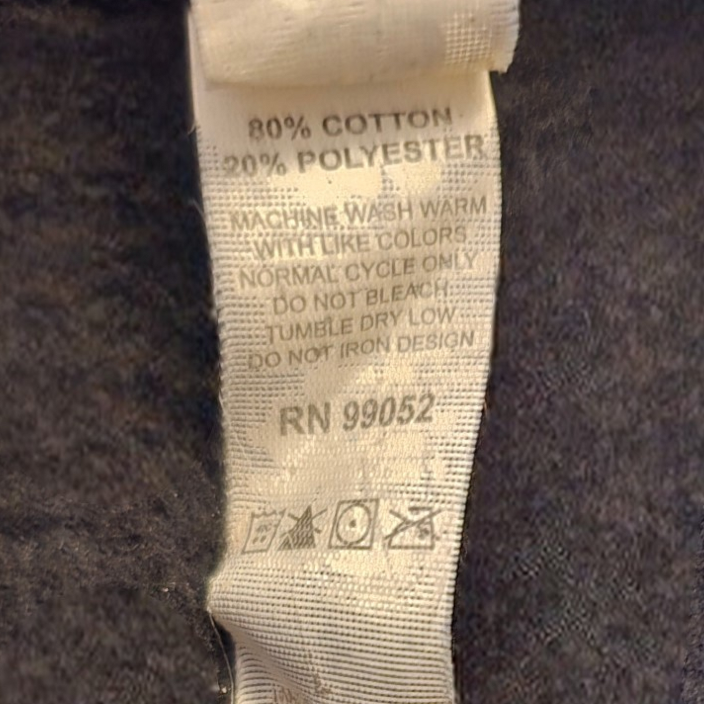 Fabric tag with washing instructions and material composition on a dark fabric background