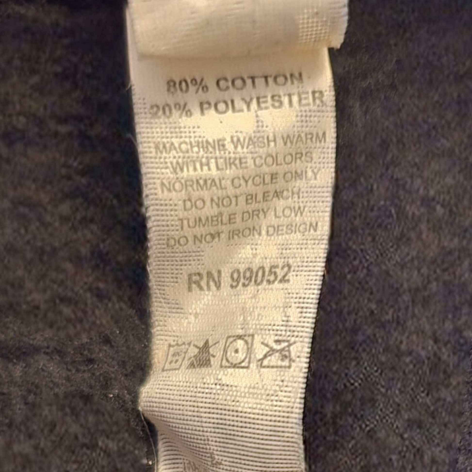 Fabric tag with washing instructions and material composition on a dark fabric background