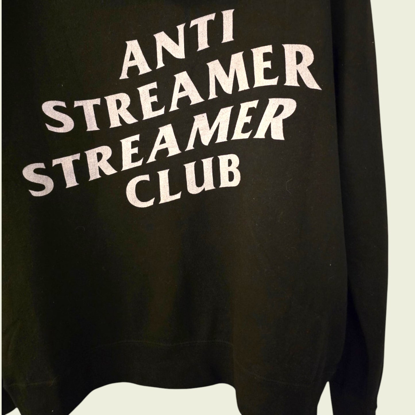 Black sweatshirt with white text 'ANTI STREAMER STREAMER CLUB' on a plain background