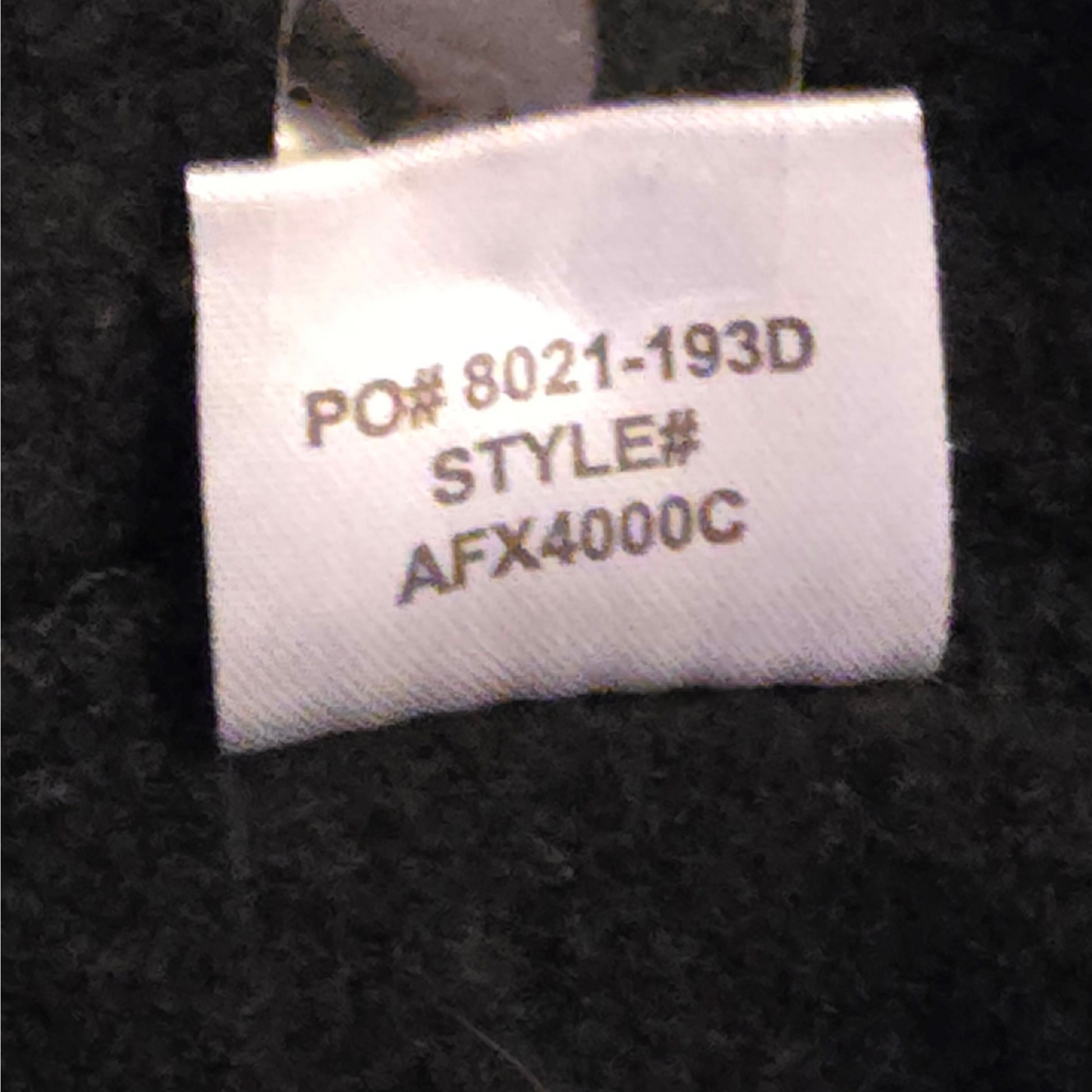 Textile label with product details on a black fabric background