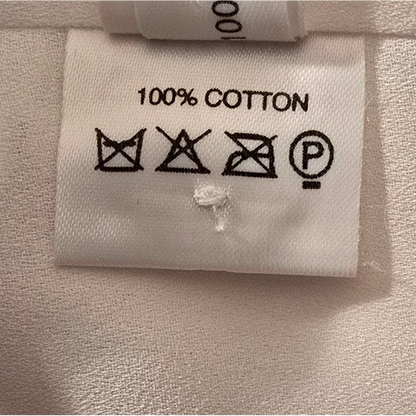Clothing label with washing instructions and a small earring on a textured surface