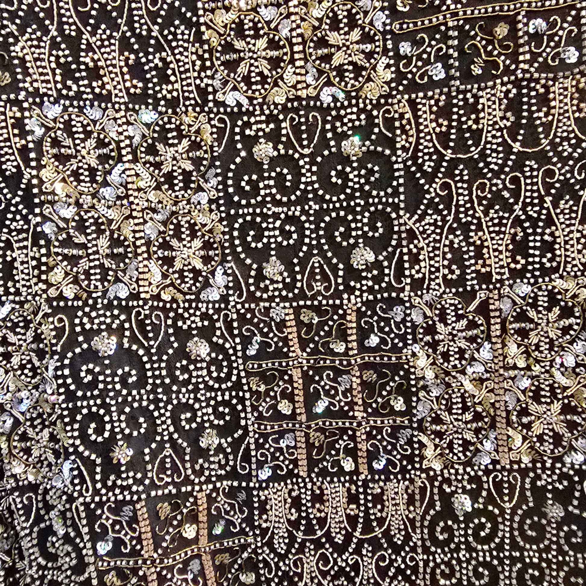 Decorative fabric with intricate patterns and embellishments on a black background