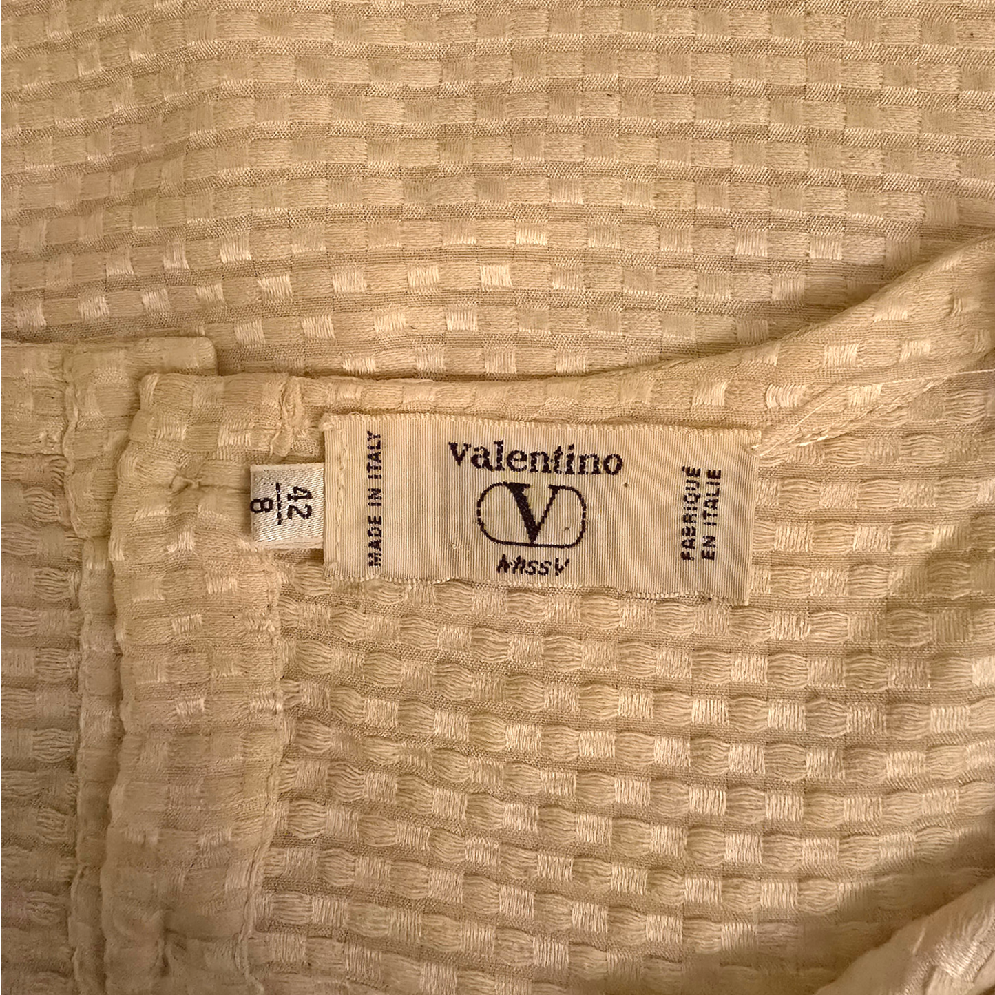 Valentino label on a textured beige fabric background
