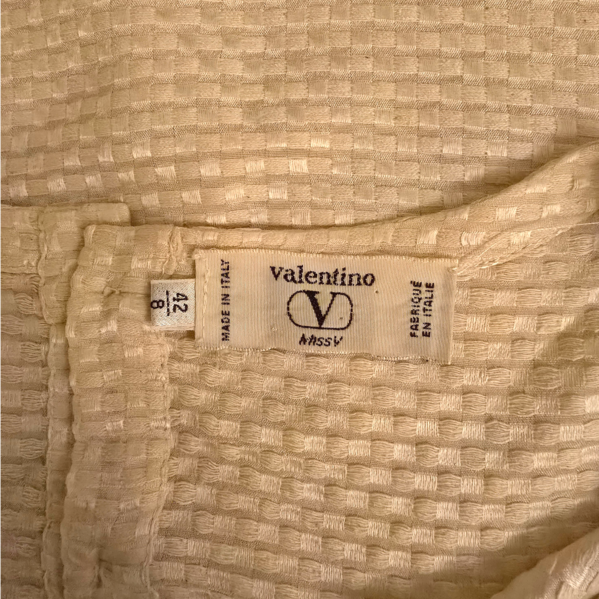 Valentino label on a textured beige fabric background