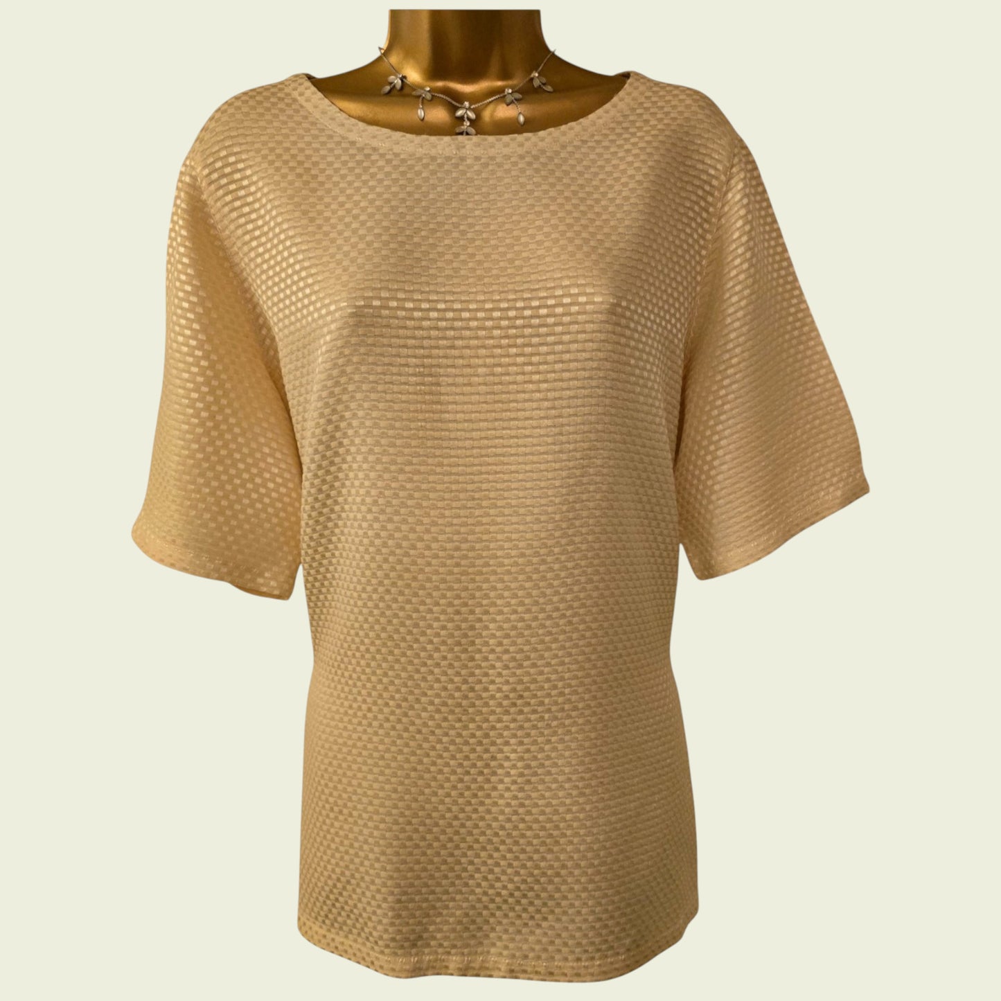 Beige textured top on a mannequin against a beige background