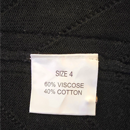 Fabric tag on black fabric with size and material information.