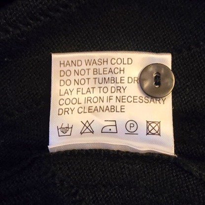 Clothing label with washing instructions on a black fabric background