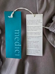 Textile with a 'medici' tag on a gray fabric background