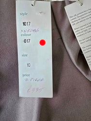 Product tag with text and a red dot on a dark fabric background