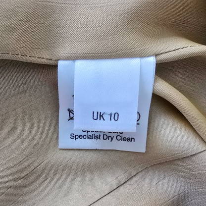 Clothing tag on beige fabric with size 'UK 10' and dry cleaning instructions.