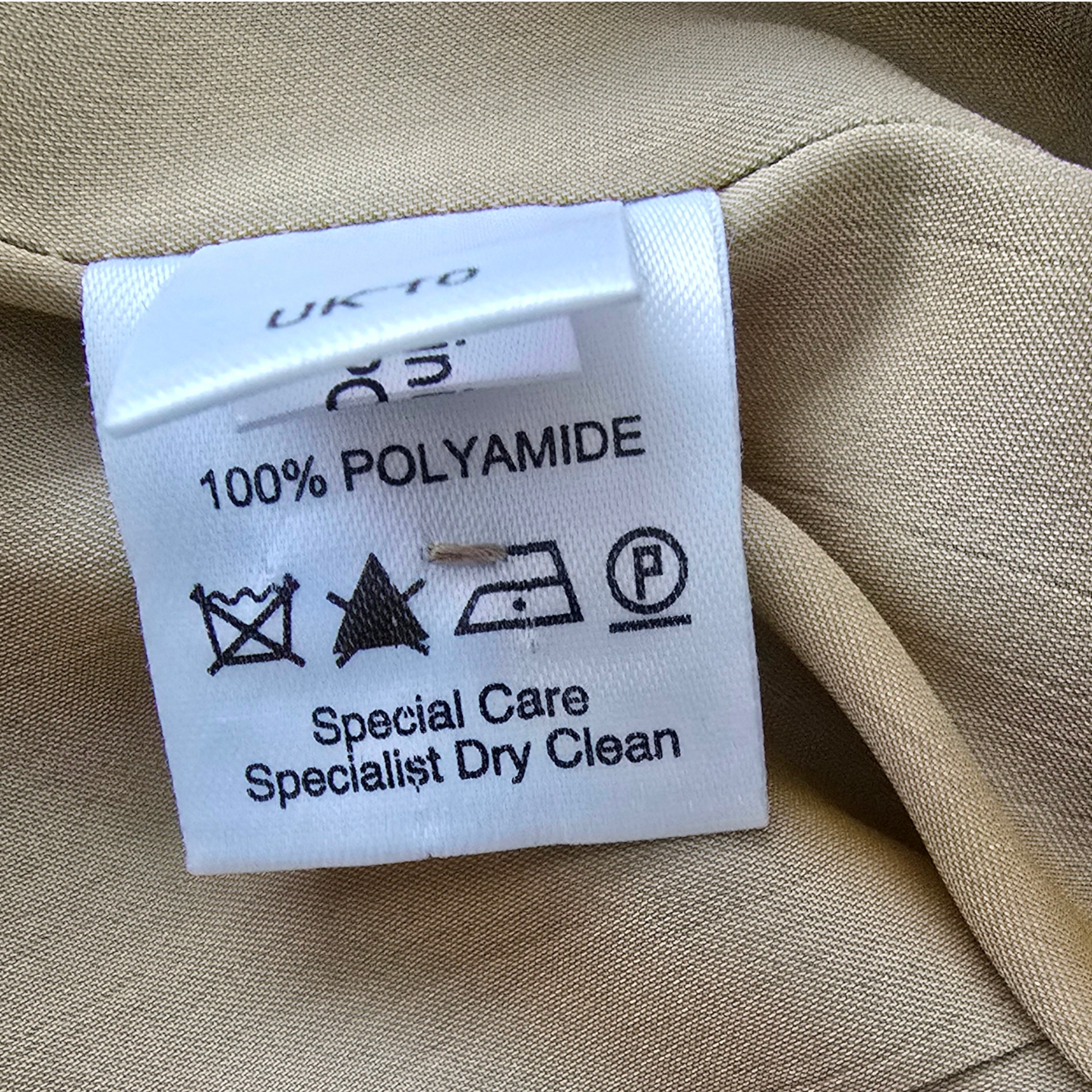 Clothing label on beige fabric with text and symbols