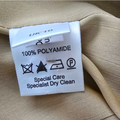 Clothing label on beige fabric with text and symbols