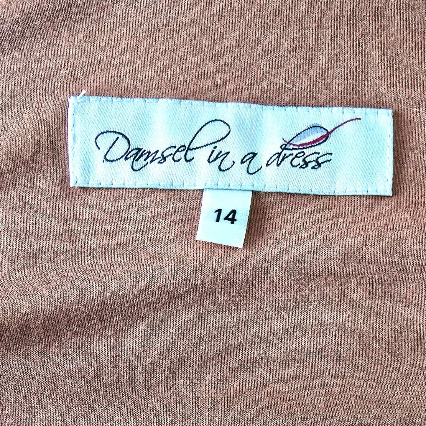 Fabric label with 'Damsel in a Dress' branding on brown fabric