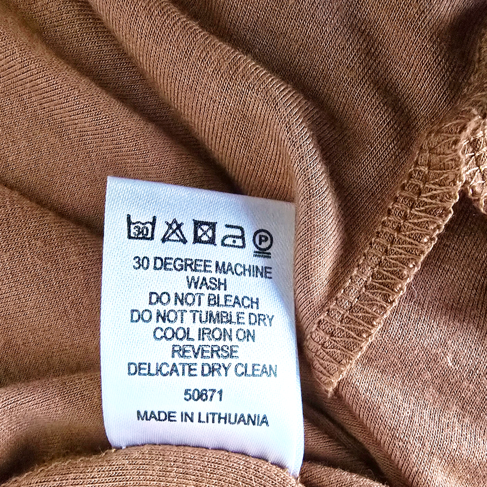 Fabric tag with care instructions on a brown fabric background