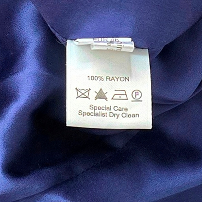 Clothing label on a piece of blue fabric with care instructions.