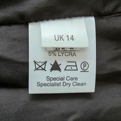 Clothing label with size 'UK 14' and care instructions on a dark fabric background