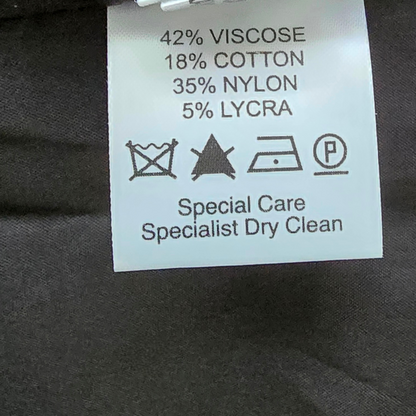 Clothing label with fabric composition and care instructions on a dark fabric background