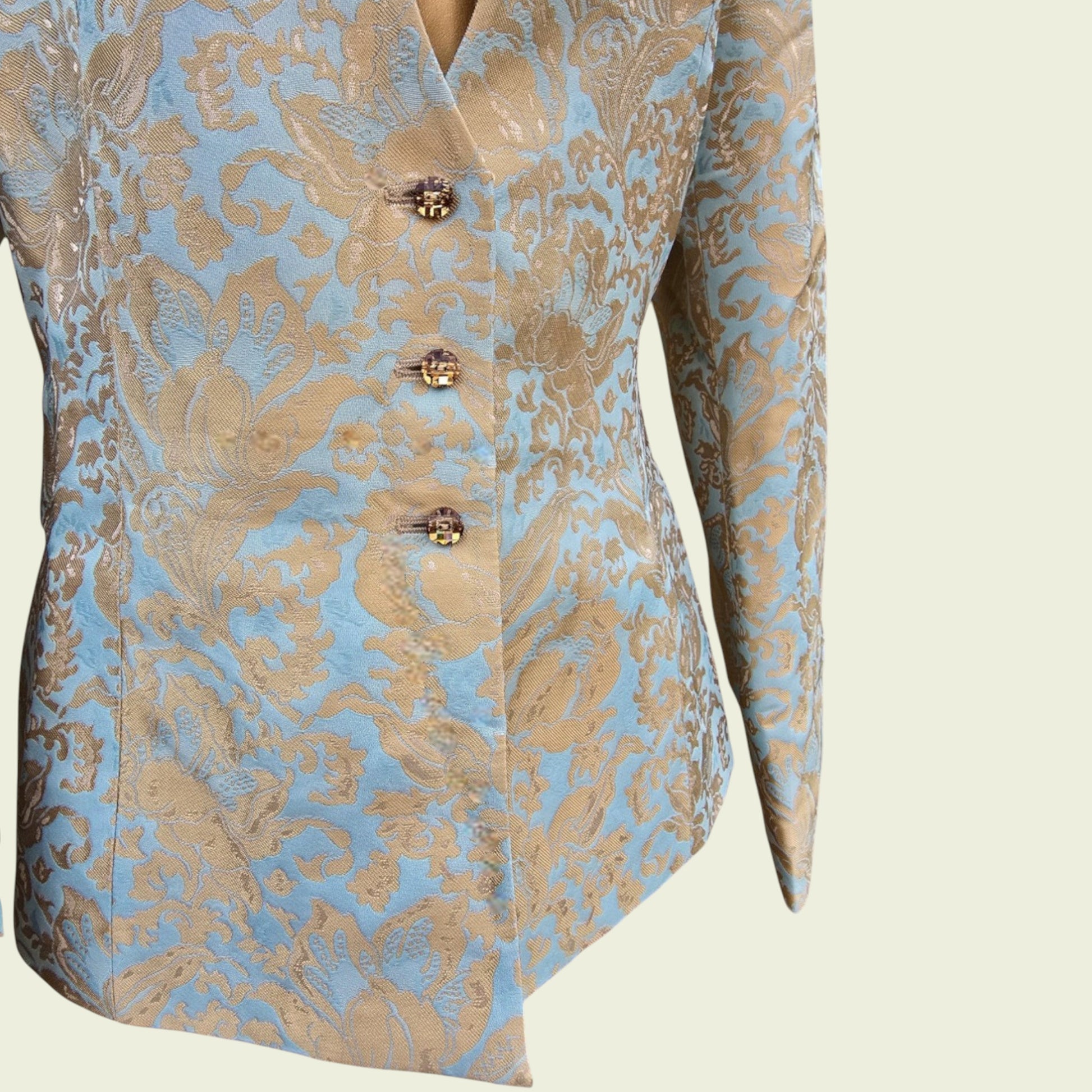 Light blue and gold jacket with button detail on a beige background