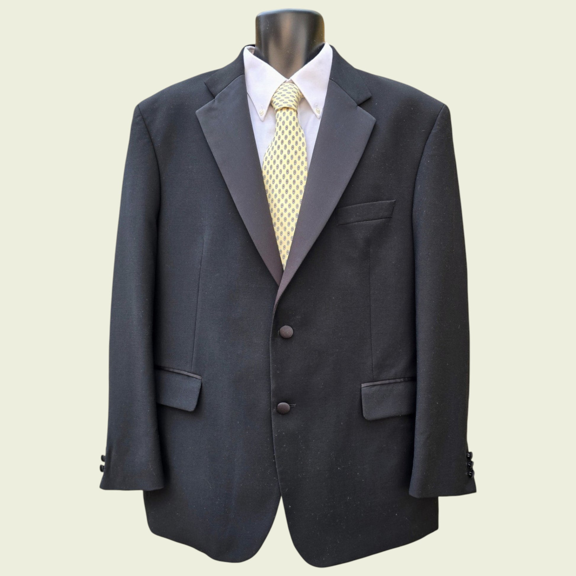 Grey suit jacket with a white shirt and yellow tie on a beige background
