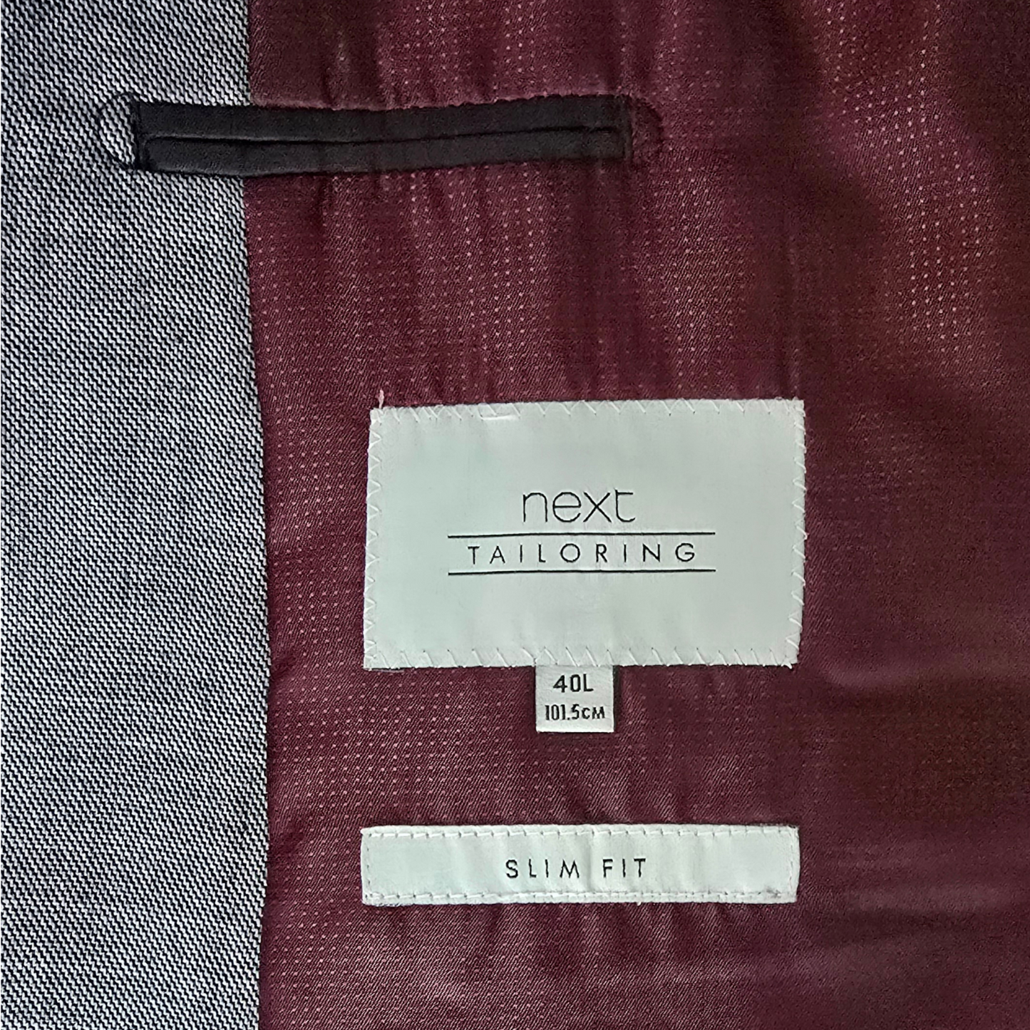 Maroon suit jacket lining with 'next tailoring' label and size information.