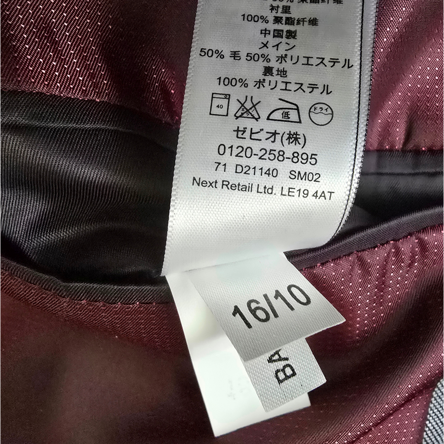 Close-up of a clothing label on a maroon fabric background