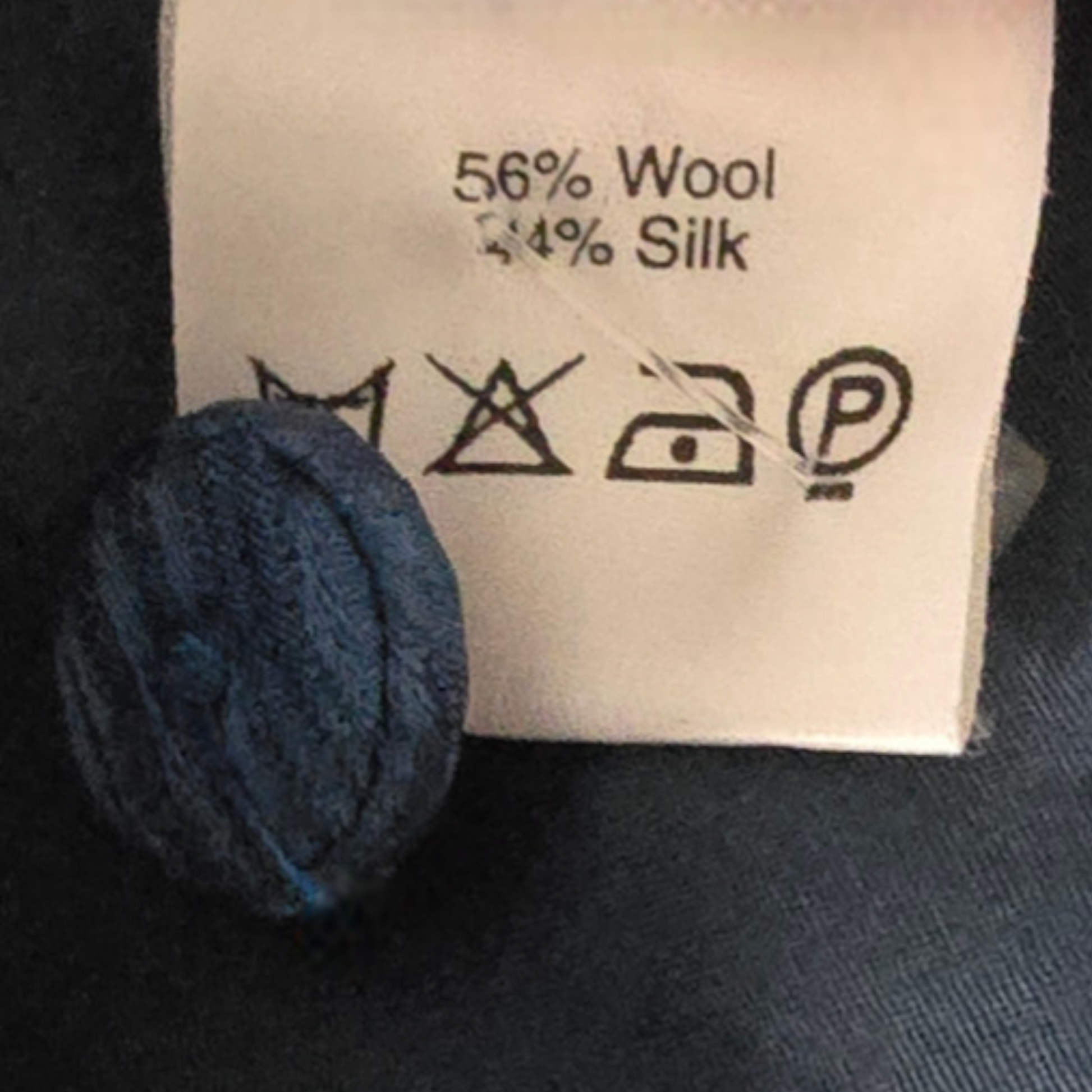 Decorative button next to a label with wool and silk content and care instructions.