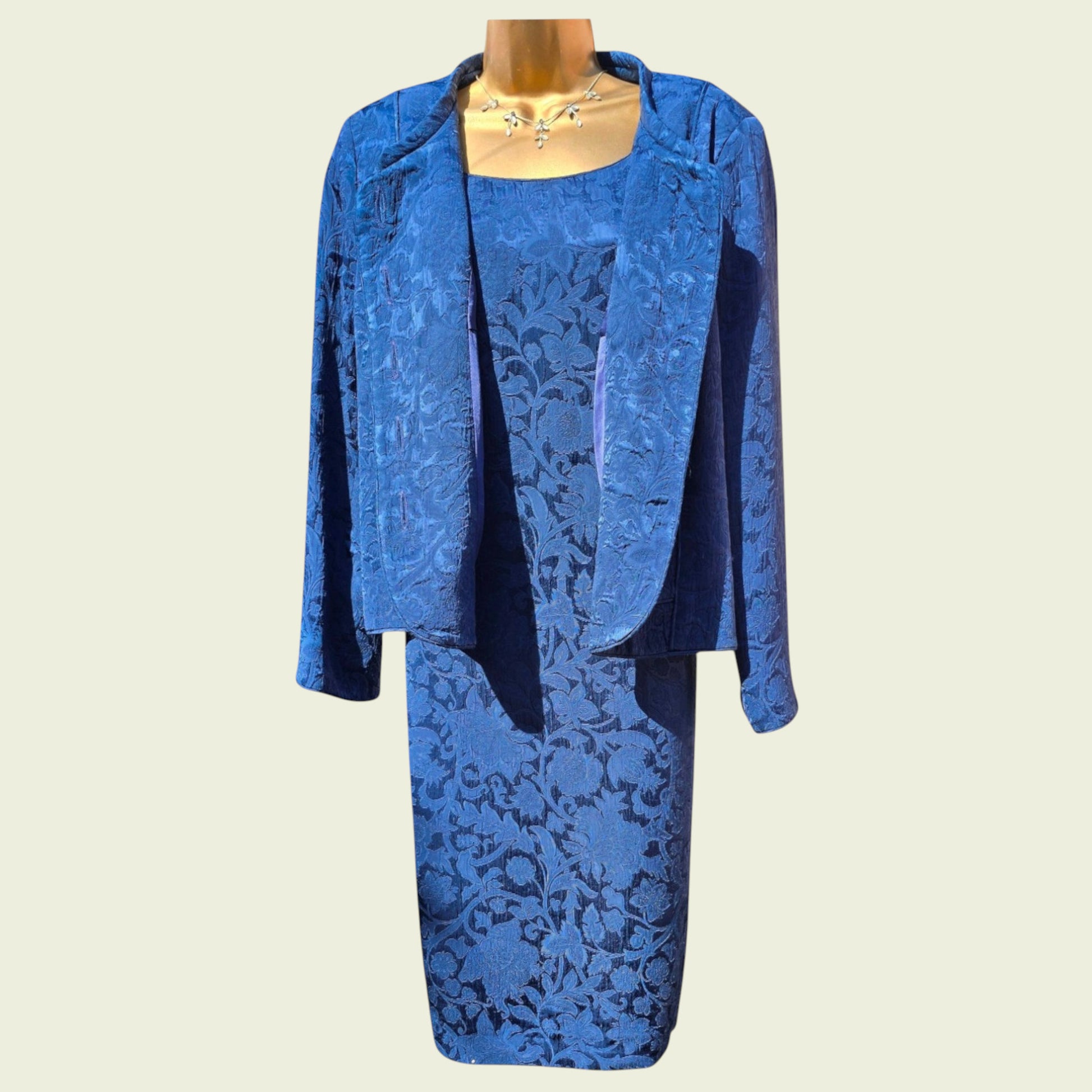 Mannequin wearing a midnight blue dress and jacket on a beige background