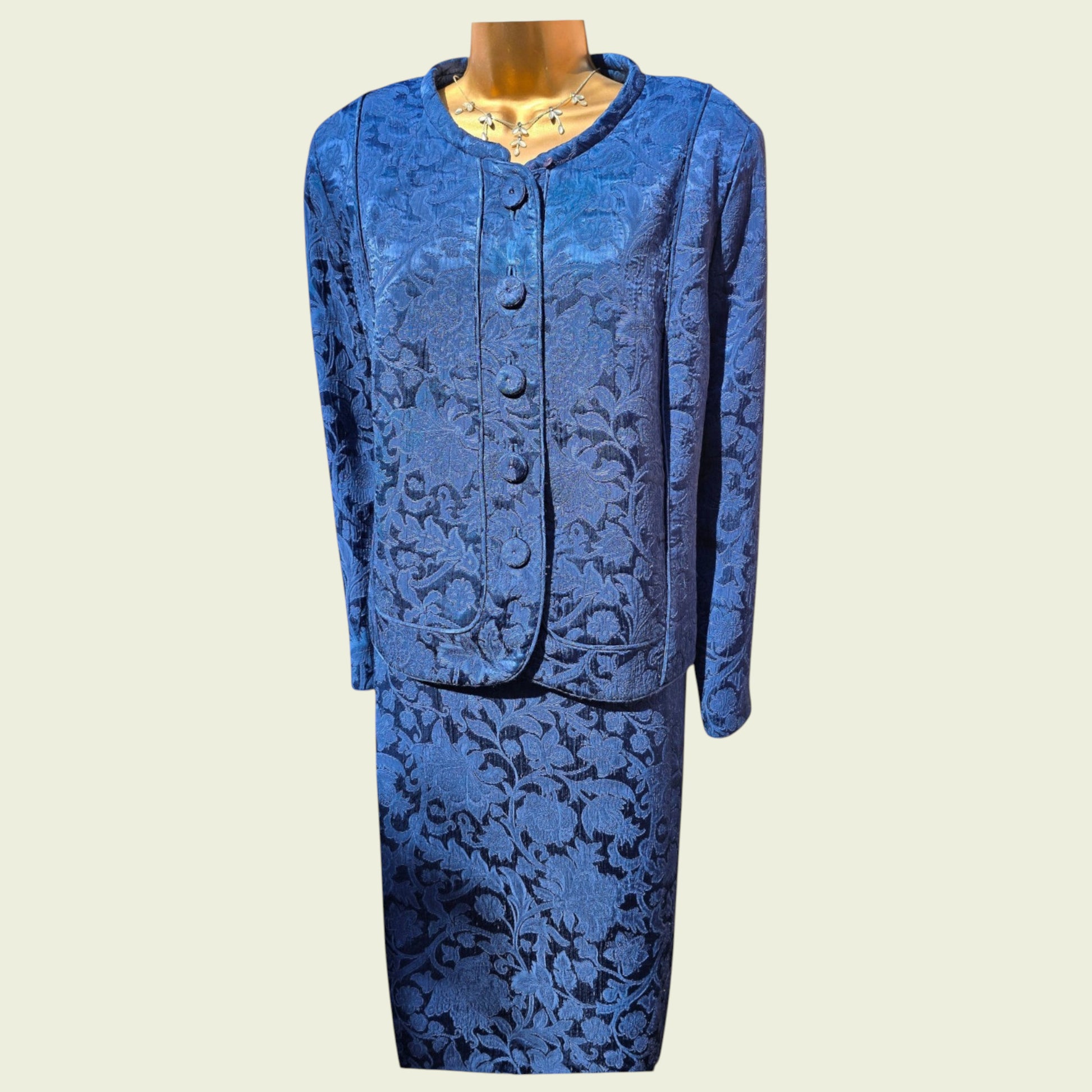 Mannequin wearing a midnight blue dress and jacket on a beige background