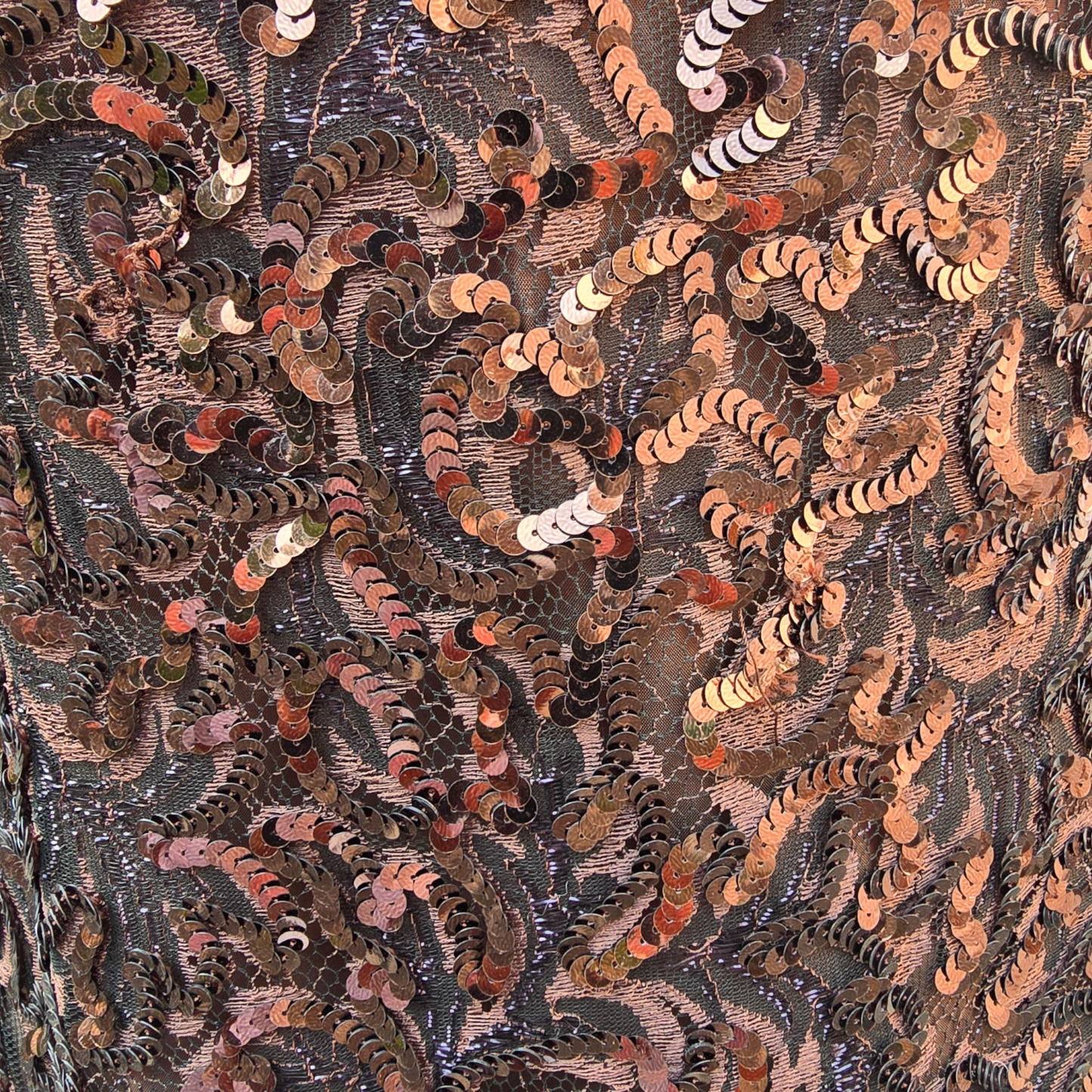 Close-up of a sequinned fabric with intricate patterns and colors.