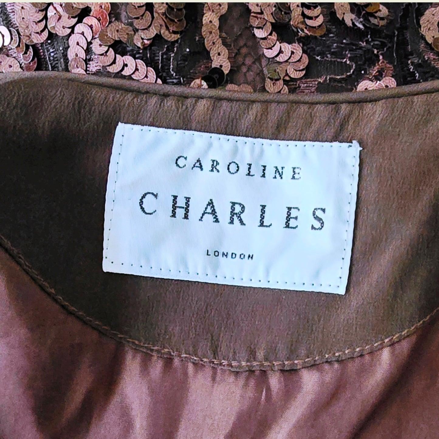 Close-up of a 'Caroline Charles London' label on a garment with sequin details.