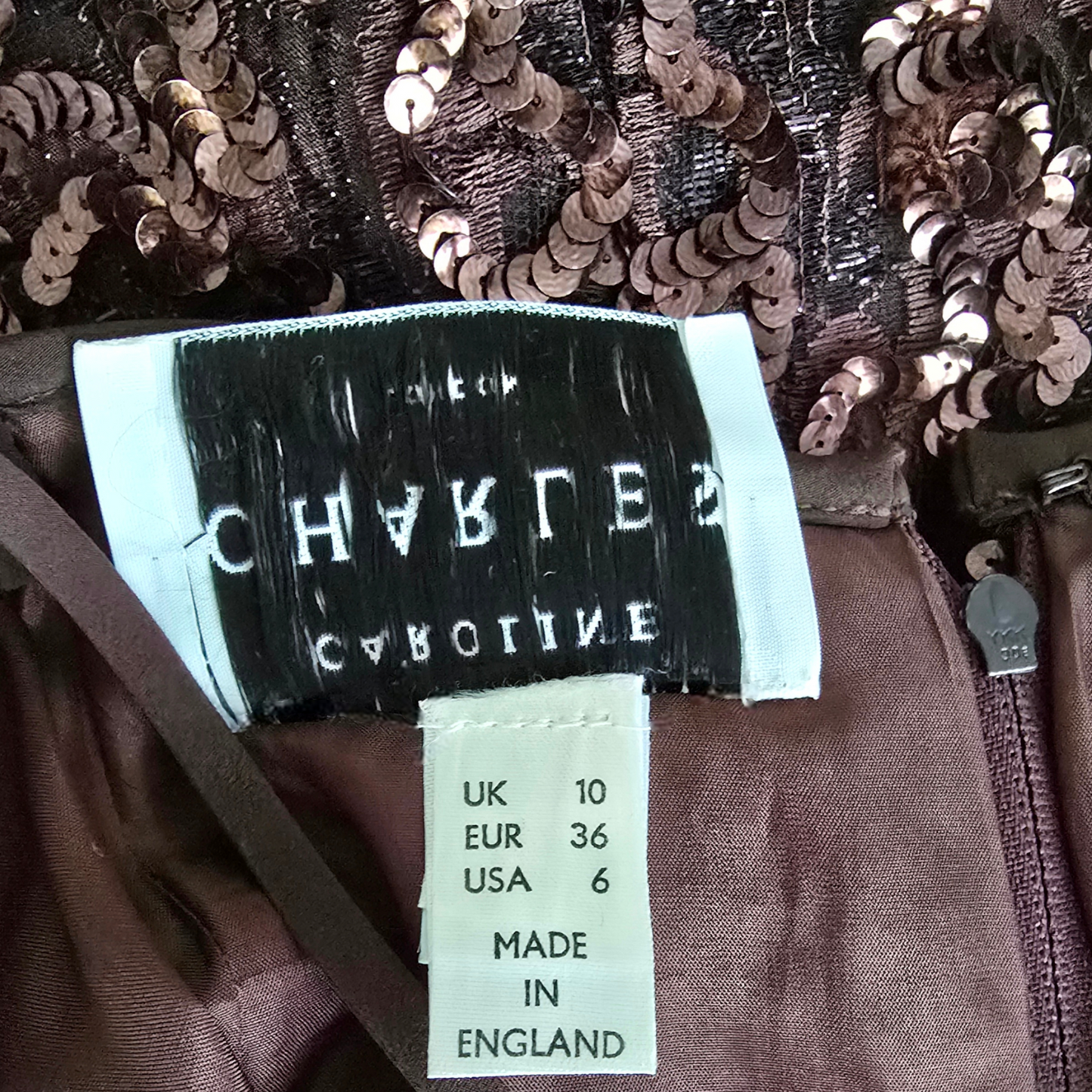 Close-up of a sequined garment with a label displaying brand name and size information.