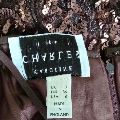 Close-up of a sequined garment with a label displaying brand name and size information.