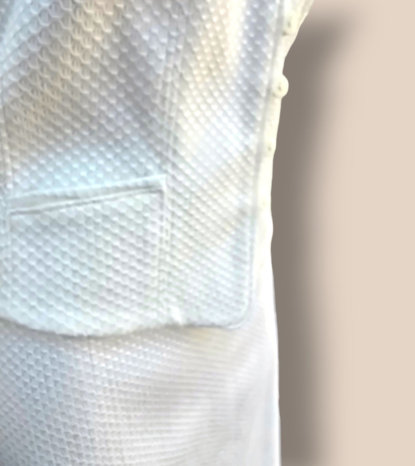 Close-up of a textured white fabric with a pocket detail.