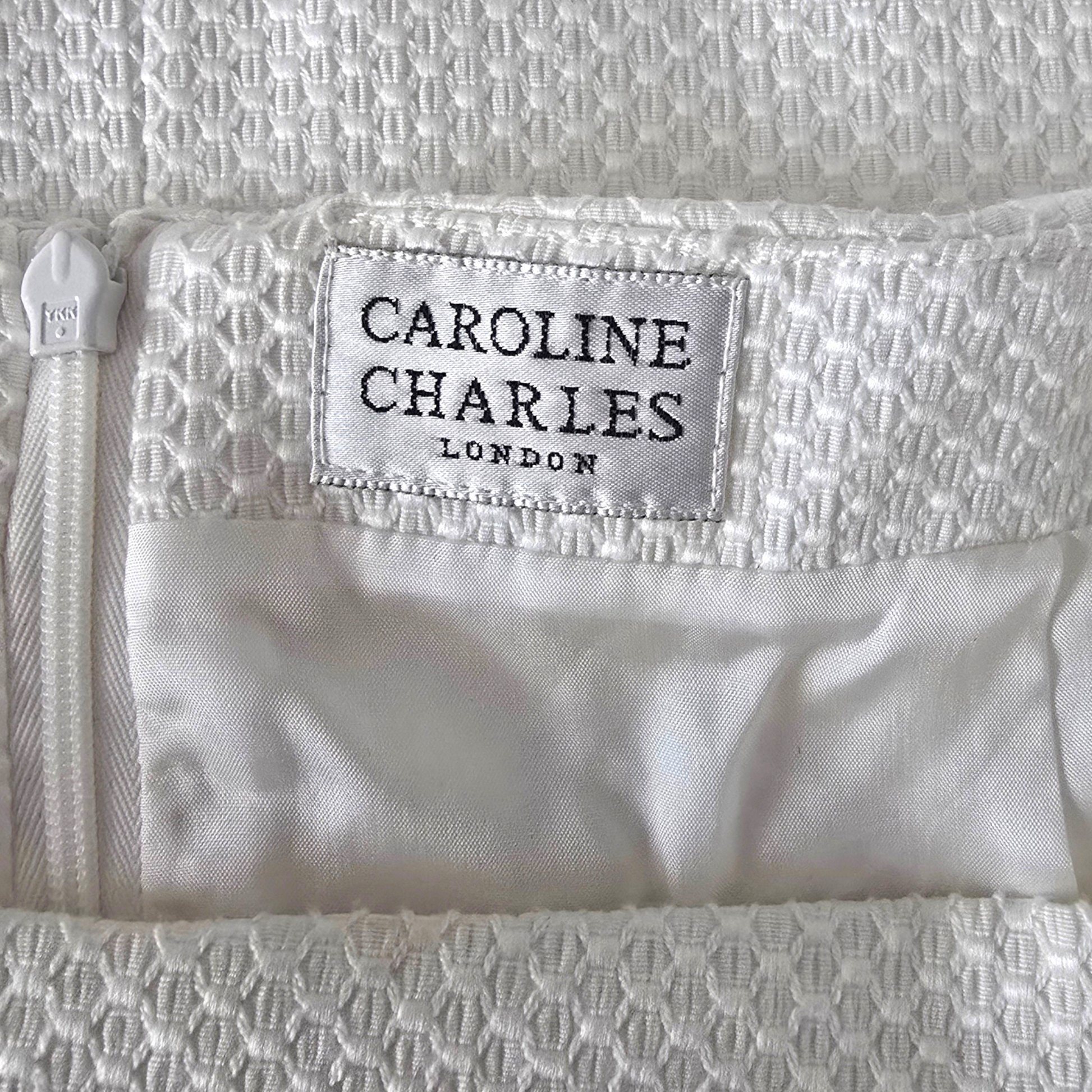 Close-up of a white textured fabric with 'Caroline Charles London' label.