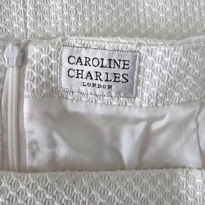 Close-up of a white textured fabric with 'Caroline Charles London' label.