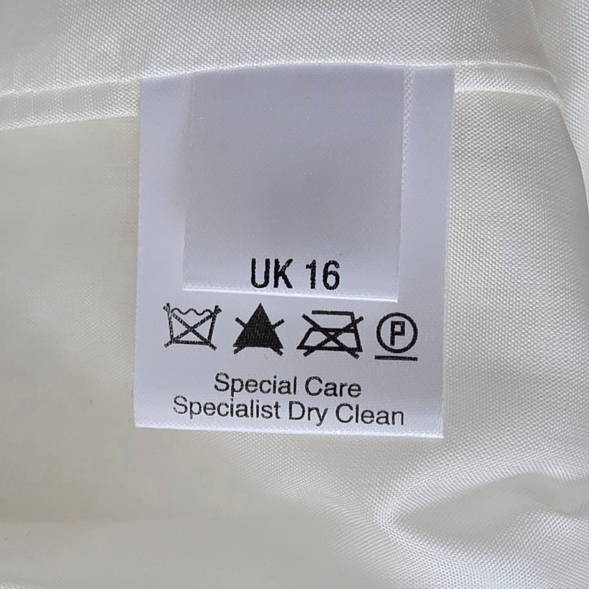 Clothing label with size 'UK 16' and care instructions on a white fabric background