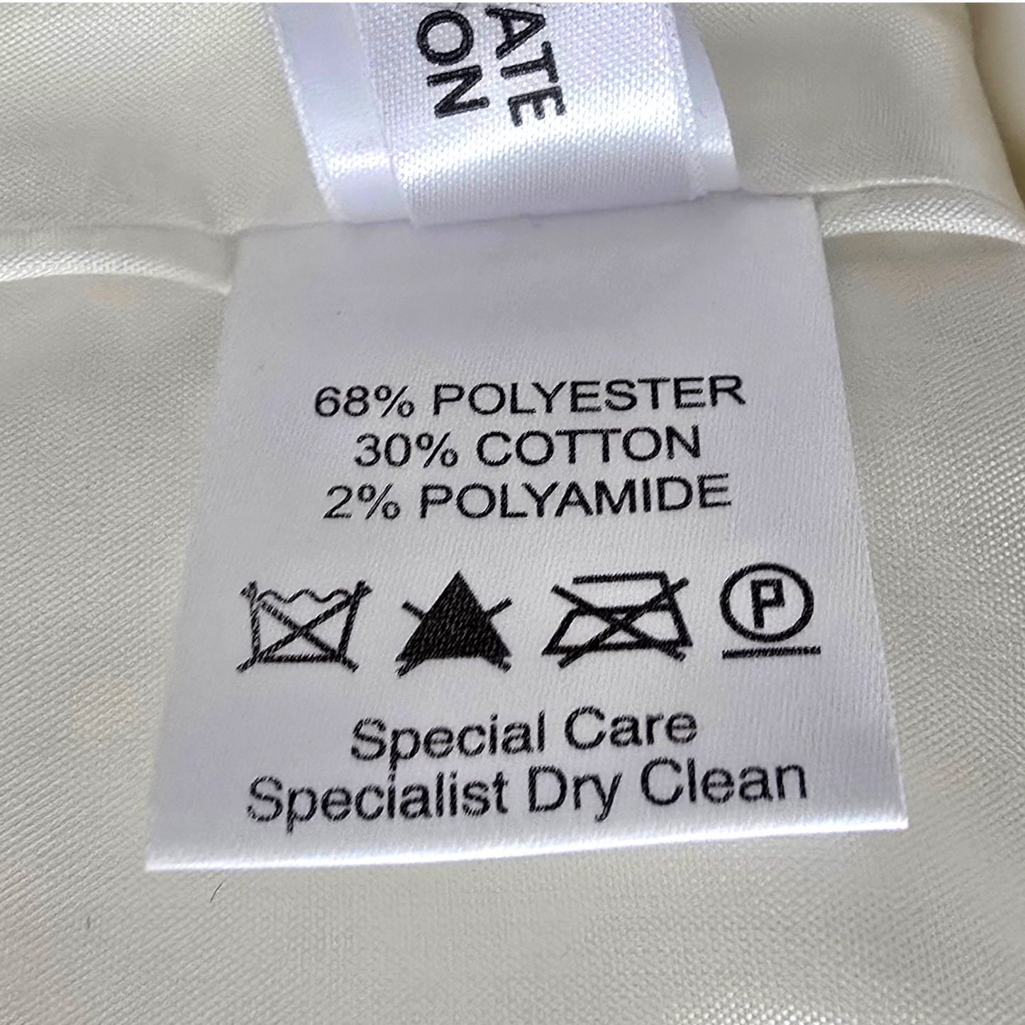 Clothing label with fabric composition and care instructions on a white fabric background
