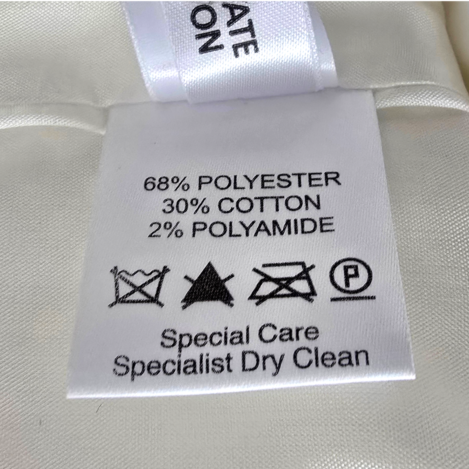 Clothing label with fabric composition and care instructions on a white fabric background