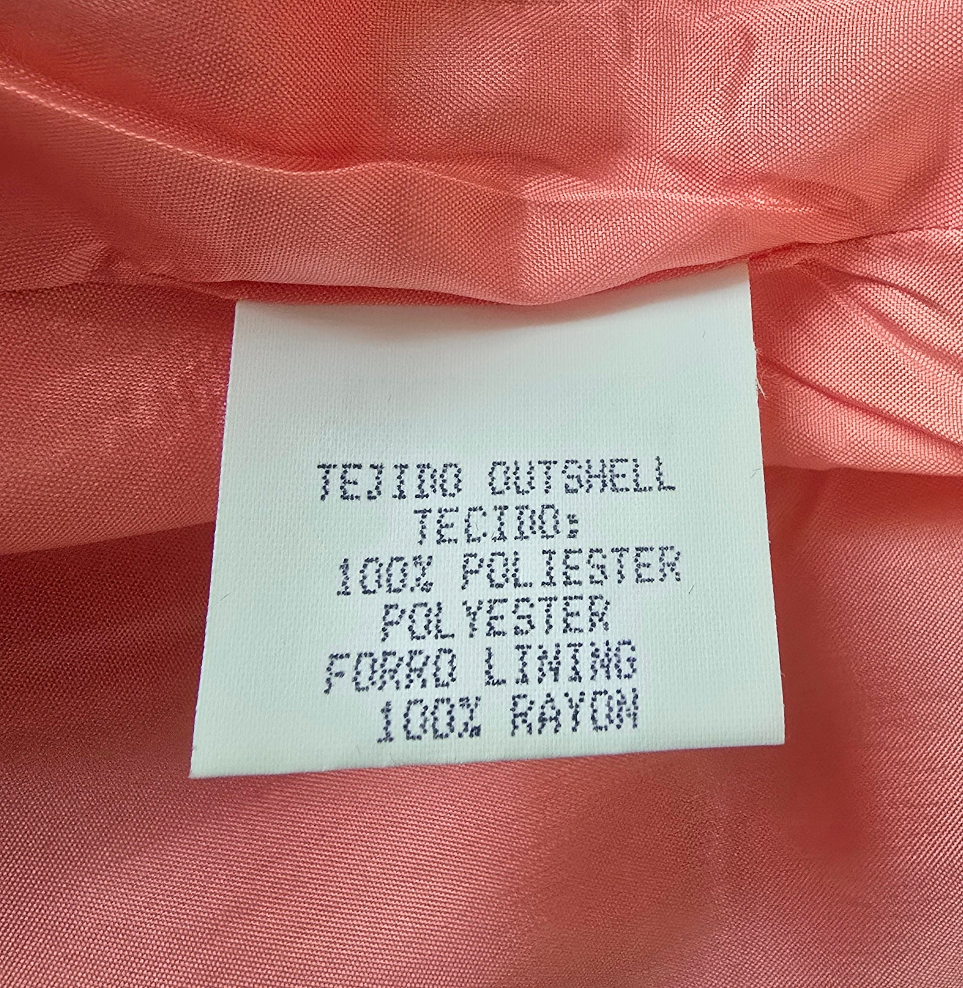 Fabric label on a pink fabric background with text about material composition.