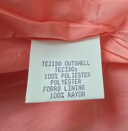 Fabric label on a pink fabric background with text about material composition.