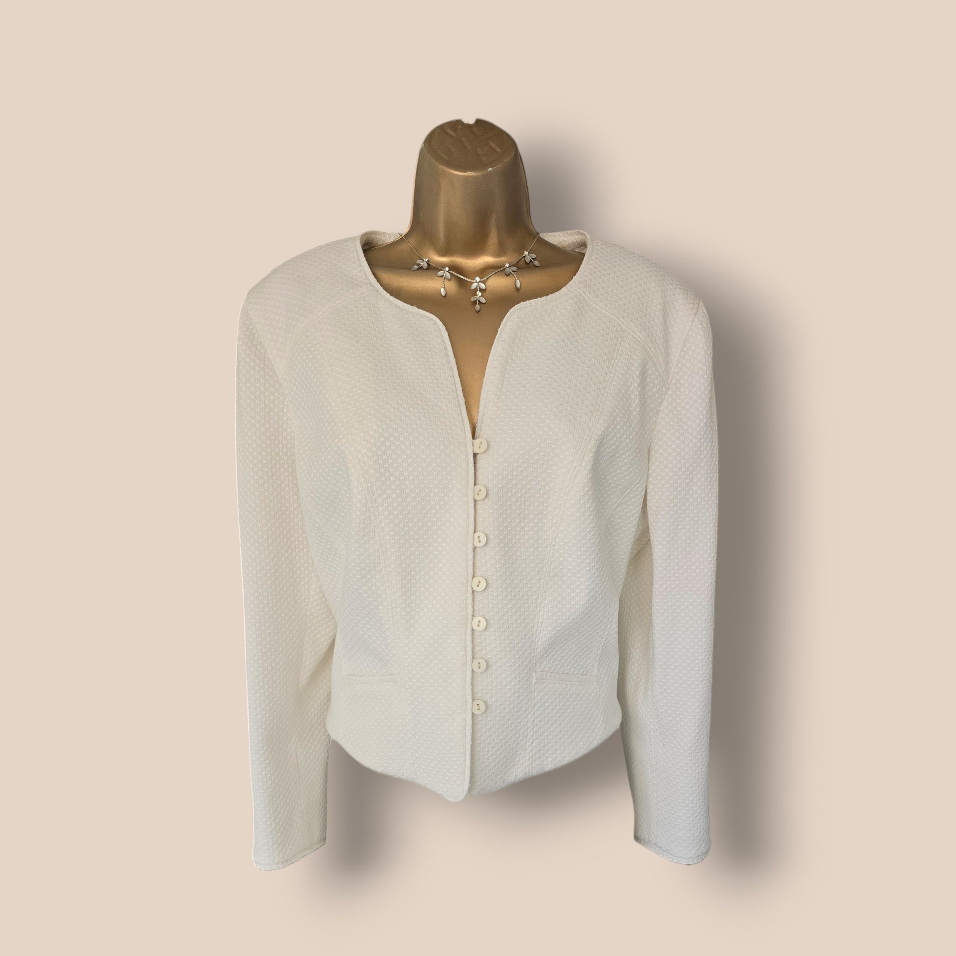 White jacket on a mannequin against a beige background