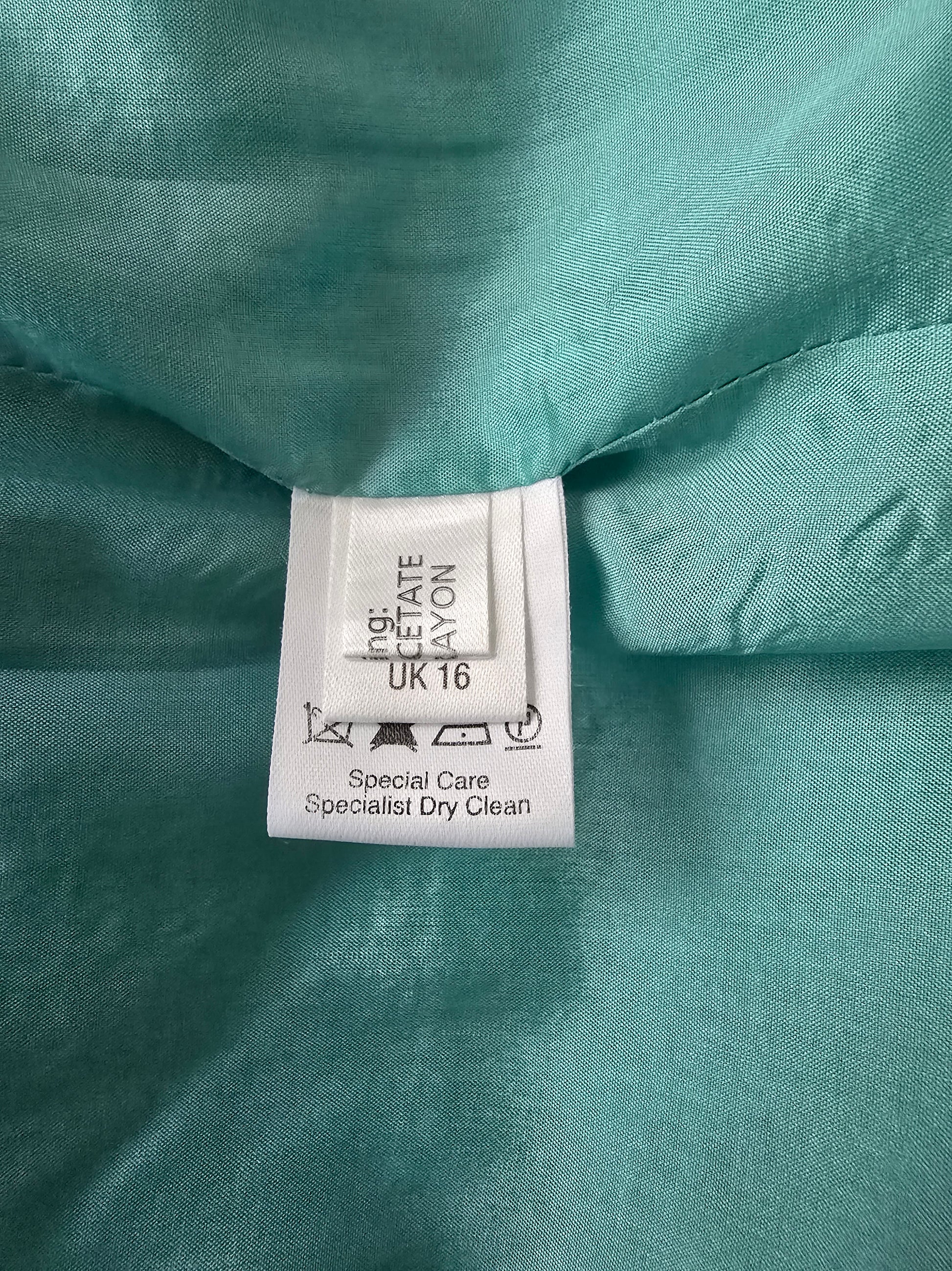 Close-up of a label on turquoise fabric with text and symbols.