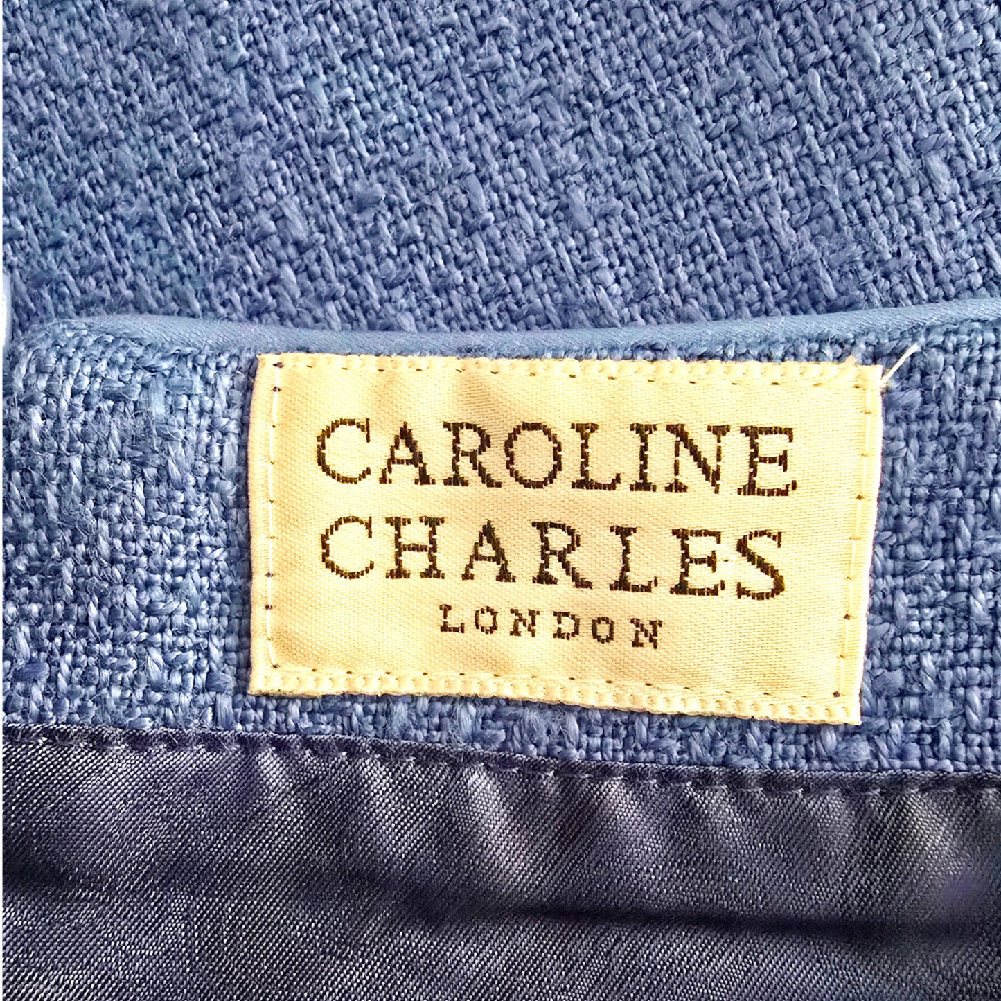 Close-up of a 'Caroline Charles London' label on blue fabric.